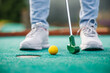 © encierro - Golfer playing adventure or mini golf and trying putting ball into hole