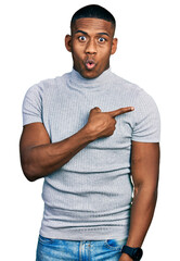 Wall Mural - Young black man wearing casual t shirt surprised pointing with finger to the side, open mouth amazed expression.