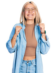 Canvas Print - Beautiful young blonde woman wearing glasses excited for success with arms raised and eyes closed celebrating victory smiling. winner concept.