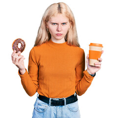 Wall Mural - Young caucasian woman eating doughnut and drinking coffee skeptic and nervous, frowning upset because of problem. negative person.