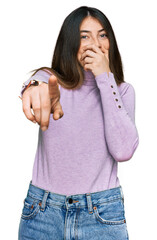 Sticker - Young beautiful teen girl wearing turtleneck sweater laughing at you, pointing finger to the camera with hand over mouth, shame expression