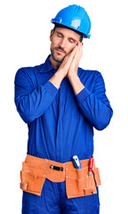 Canvas Print - Young handsome man wearing worker uniform and hardhat sleeping tired dreaming and posing with hands together while smiling with closed eyes.