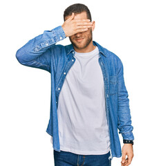 Wall Mural - Young caucasian man wearing casual clothes covering eyes with hand, looking serious and sad. sightless, hiding and rejection concept