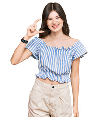 Wall Mural - Young beautiful caucasian girl wearing casual clothes smiling and confident gesturing with hand doing small size sign with fingers looking and the camera. measure concept.