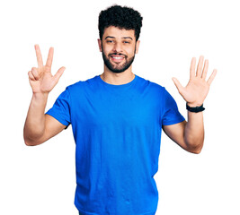 Poster - Young arab man with beard wearing casual blue t shirt showing and pointing up with fingers number eight while smiling confident and happy.