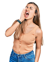 Wall Mural - Hispanic young woman wearing casual summer shirt shouting and screaming loud to side with hand on mouth. communication concept.