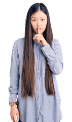 Poster - Young beautiful chinese woman wearing casual shirt asking to be quiet with finger on lips. silence and secret concept.