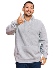 Sticker - Handsome man with tattoos wearing casual sweatshirt smiling happy and positive, thumb up doing excellent and approval sign