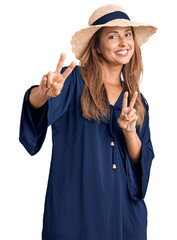 Sticker - Middle age hispanic woman wearing summer hat smiling looking to the camera showing fingers doing victory sign. number two.