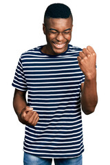 Young african american man wearing casual striped t shirt celebrating surprised and amazed for success with arms raised and eyes closed