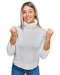 © Krakenimages.com - Beautiful blonde woman wearing casual turtleneck sweater celebrating surprised and amazed for success with arms raised and open eyes. winner concept.