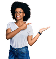 Wall Mural - Young african american woman wearing casual white t shirt amazed and smiling to the camera while presenting with hand and pointing with finger.