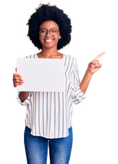 Wall Mural - Young african american woman holding blank empty paper smiling happy pointing with hand and finger to the side