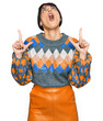 © Krakenimages.com - Young hispanic woman wearing casual clothes amazed and surprised looking up and pointing with fingers and raised arms.