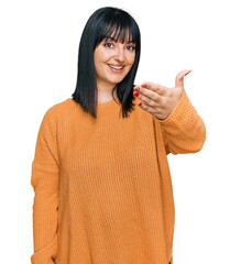 Canvas Print - Young hispanic woman wearing casual clothes smiling friendly offering handshake as greeting and welcoming. successful business.