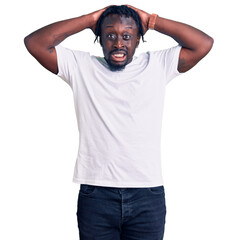 Canvas Print - Young african american man with braids wearing casual white tshirt crazy and scared with hands on head, afraid and surprised of shock with open mouth