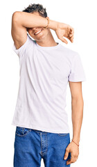 Wall Mural - Young handsome man wearing casual white tshirt covering eyes with arm smiling cheerful and funny. blind concept.