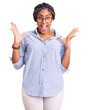 © Krakenimages.com - Young african american woman with braids wearing casual clothes and glasses celebrating crazy and amazed for success with arms raised and open eyes screaming excited. winner concept