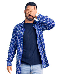 Wall Mural - Young hispanic man wearing casual clothes covering eyes with hand, looking serious and sad. sightless, hiding and rejection concept