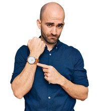 Young Hispanic Man Wearing Casual Clothes In Hurry Pointing To Watch Time, Impatience, Looking At The Camera With Relaxed Expression