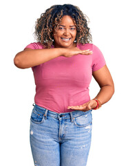 Wall Mural - Young african american plus size woman wearing casual clothes gesturing with hands showing big and large size sign, measure symbol. smiling looking at the camera. measuring concept.