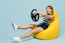Full Body Young Woman She Wear Striped Tank Shirt Casual Clothes Sit In Bag Chair Hold Steering Wheel Driving Car Isolated On Plain Pastel Light Blue Cyan Background Studio Portrait Lifestyle Concept