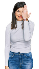 Wall Mural - Beautiful brunette woman wearing casual clothes covering one eye with hand, confident smile on face and surprise emotion.