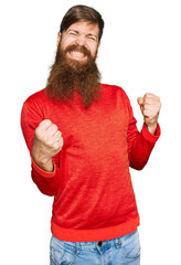 Wall Mural - Redhead man with long beard wearing casual clothes very happy and excited doing winner gesture with arms raised, smiling and screaming for success. celebration concept.