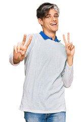 Sticker - Young hispanic man wearing casual clothes smiling looking to the camera showing fingers doing victory sign. number two.