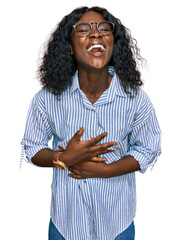 Poster - Beautiful african young woman wearing casual clothes and glasses smiling and laughing hard out loud because funny crazy joke with hands on body.