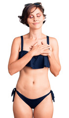 Wall Mural - Beautiful young woman with short hair wearing bikini smiling with hands on chest with closed eyes and grateful gesture on face. health concept.