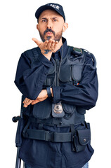 Poster - Young handsome man wearing police uniform looking at the camera blowing a kiss with hand on air being lovely and sexy. love expression.