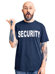 Sticker - Young handsome man wearing security t shirt surprised pointing with hand finger to the side, open mouth amazed expression.