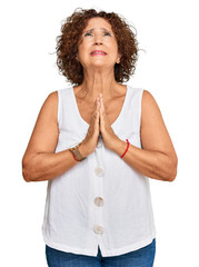 Canvas Print - Beautiful middle age mature woman wearing casual white shirt begging and praying with hands together with hope expression on face very emotional and worried. begging.