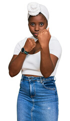 Poster - Young african woman with turban wearing hair turban over isolated background ready to fight with fist defense gesture, angry and upset face, afraid of problem