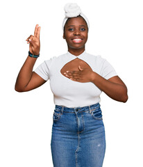 Sticker - Young african woman with turban wearing hair turban over isolated background smiling swearing with hand on chest and fingers up, making a loyalty promise oath