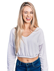 Poster - Beautiful young blonde woman wearing casual white sweater winking looking at the camera with sexy expression, cheerful and happy face.