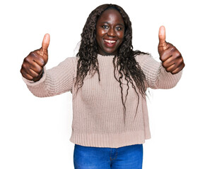 Sticker - Young african woman wearing wool winter sweater approving doing positive gesture with hand, thumbs up smiling and happy for success. winner gesture.