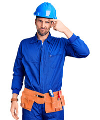 Canvas Print - Young handsome man wearing worker uniform and hardhat covering eyes with hand, looking serious and sad. sightless, hiding and rejection concept