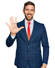 Sticker - Handsome man with beard wearing business suit and tie showing and pointing up with fingers number five while smiling confident and happy.