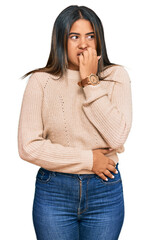 Poster - Young latin girl wearing wool winter sweater looking stressed and nervous with hands on mouth biting nails. anxiety problem.