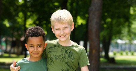 Wall Mural - Two cheerful boys in a green T-shirt posing in a summer park