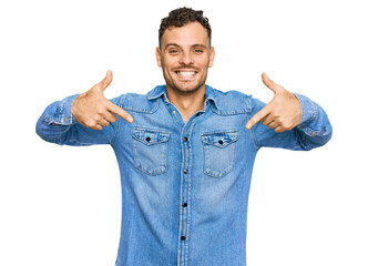 Canvas Print - Young hispanic man wearing casual denim jacket looking confident with smile on face, pointing oneself with fingers proud and happy.