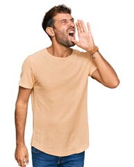 Canvas Print - Handsome young man with beard wearing casual tshirt shouting and screaming loud to side with hand on mouth. communication concept.