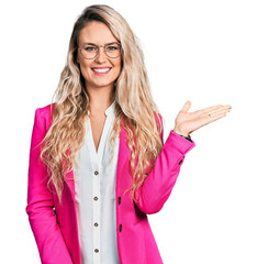 Wall Mural - Young blonde woman wearing business style and glasses smiling cheerful presenting and pointing with palm of hand looking at the camera.