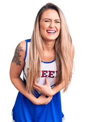 Poster - Young beautiful blonde woman wearing cheerleader uniform smiling and laughing hard out loud because funny crazy joke with hands on body.