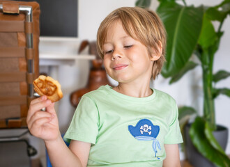 Cute blond five years old boy have a lunch at home