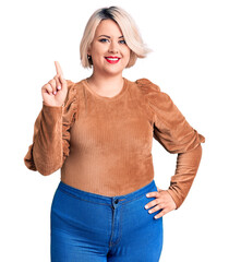 Wall Mural - Young blonde plus size woman wearing casual sweater showing and pointing up with finger number one while smiling confident and happy.