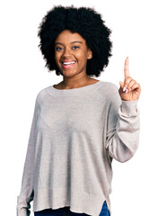 Poster - Young african american woman wearing casual clothes showing and pointing up with finger number one while smiling confident and happy.