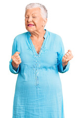 Wall Mural - Senior beautiful woman with blue eyes and grey hair wearing summer dress excited for success with arms raised and eyes closed celebrating victory smiling. winner concept.